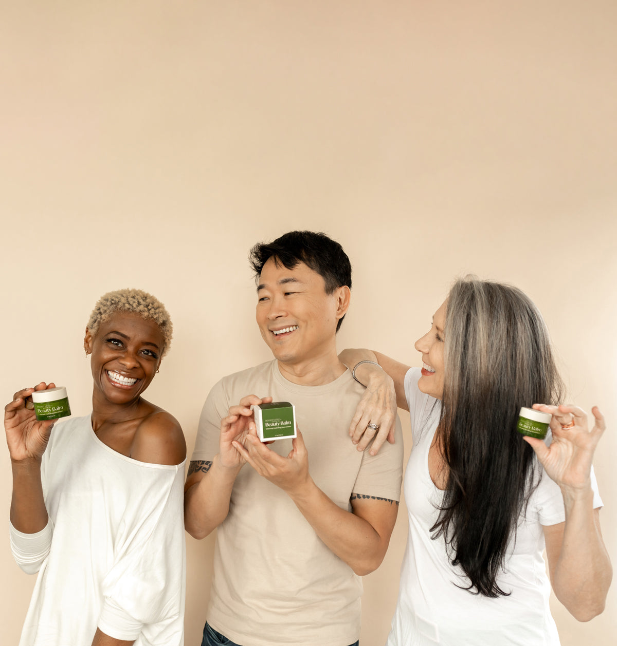 three people holding green jars and green packaging of the Beauty Balm